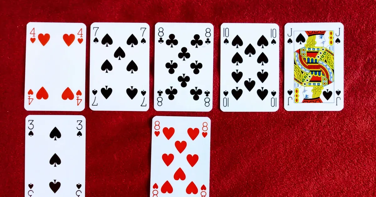Playing cards laid out in rows on red felt