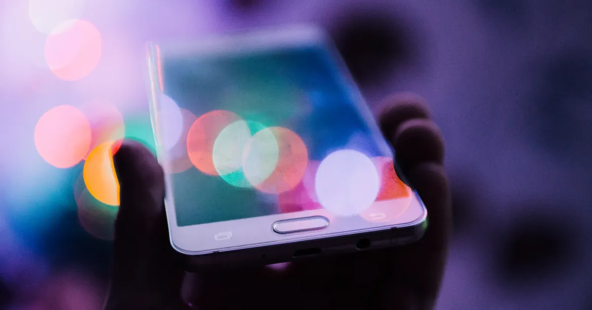 Smartphone held in hand against colourful bokeh lights