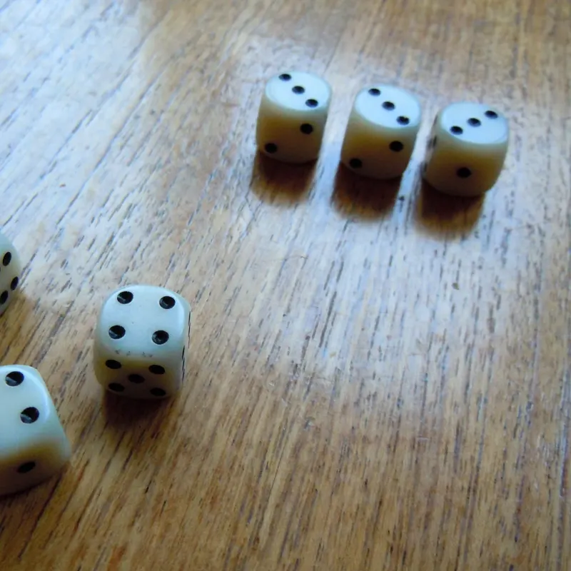 Six white dice scattered on a wooden table